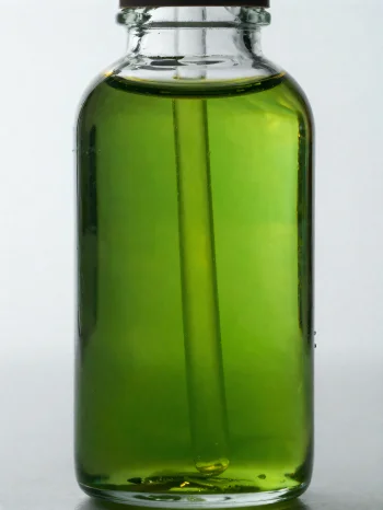 Avokadoolja i liten flaska och skål mot ljus, neutral bakgrund