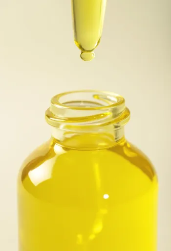 Citronolja i liten flaska bredvid färska citronskivor och rivet skal