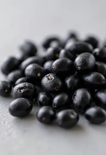 Blanka, råa och kokta svarta bönor i en keramikskål på ett rustikt bord