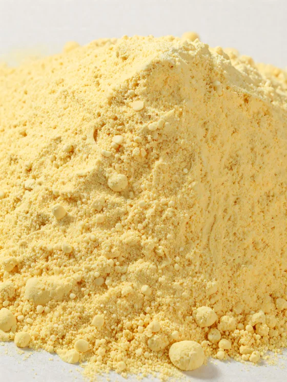 Majsmjöl i en keramikskål, gult pulvermjöl på en träyta