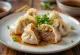 Kinesiska Pekinganka jiaozi kokta, på vit tallrik, ankfyllning synlig