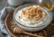 Kanel- och kokosyoghurtdryck serverad i glas, i ljus krämig nyans, med lite kokosflingor på toppen