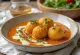 Malai Kofta curry serverad i rik, krämig sås, garnerad med färsk koriander.