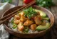 Poké bowl med kyckling, färska grönsaker på risbädd, garnerad med koriander och limejuice.