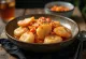 Tteokbokki med fiskkaka, serverad med sesamfrön och salladslök